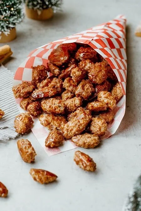 Leckere gebrannte Mandeln in einer Schüssel auf Holzuntergrund