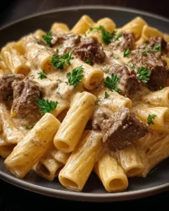 Rigatoni mit Rindfleisch und Parmesansoße auf einem Teller angerichtet