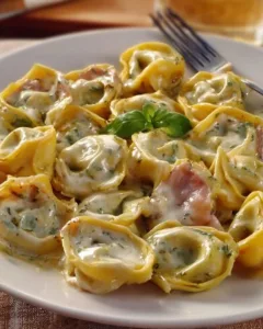 Tortellini mit Sahne auf einem Teller, verziert mit frisch gehacktem Basilikum.