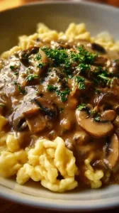 Authentische deutsche Spätzle mit Pilzsoße serviert auf einem Teller.