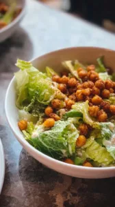 Einfacher Caesar-Salat mit knusprigen Kichererbsen-Croûtons auf einem Teller.