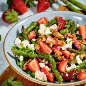 Grüner Spargel Erdbeer Salat mit karamellisierten Nüssen auf einem Teller