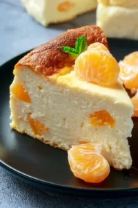 Leckerer Käsekuchen mit Mandarinen auf einem Teller serviert.